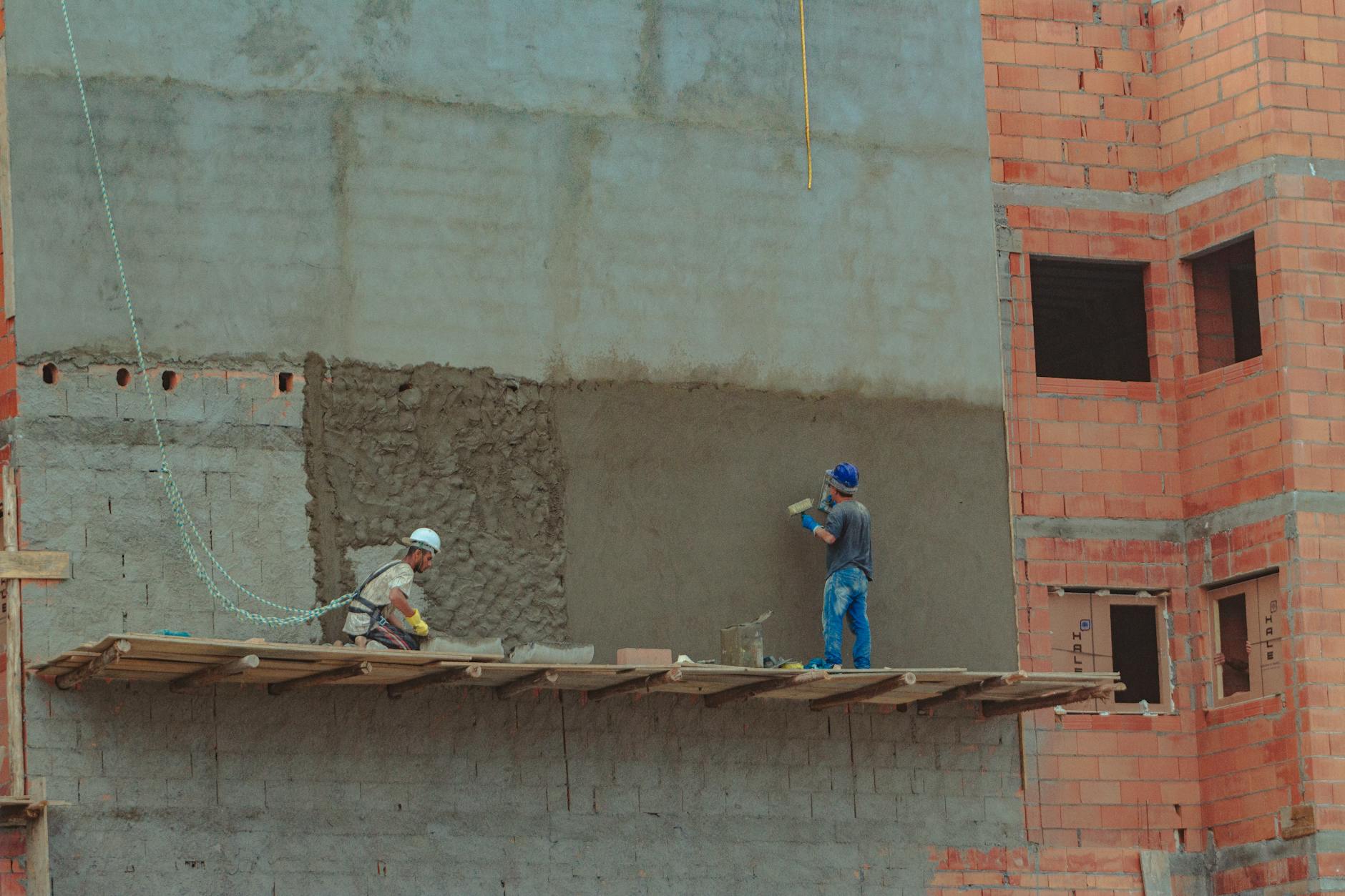 Homem em capacete e cinto de segurança em plataforma de trabalho em altura. — Medicina Ocupacional Curitiba