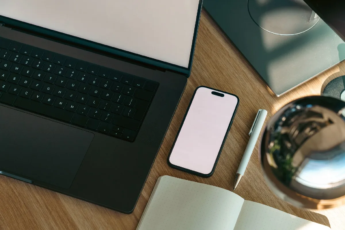 Vista aérea de um escritório moderno com laptop, celular e caderno. — Medicina Ocupacional Curitiba