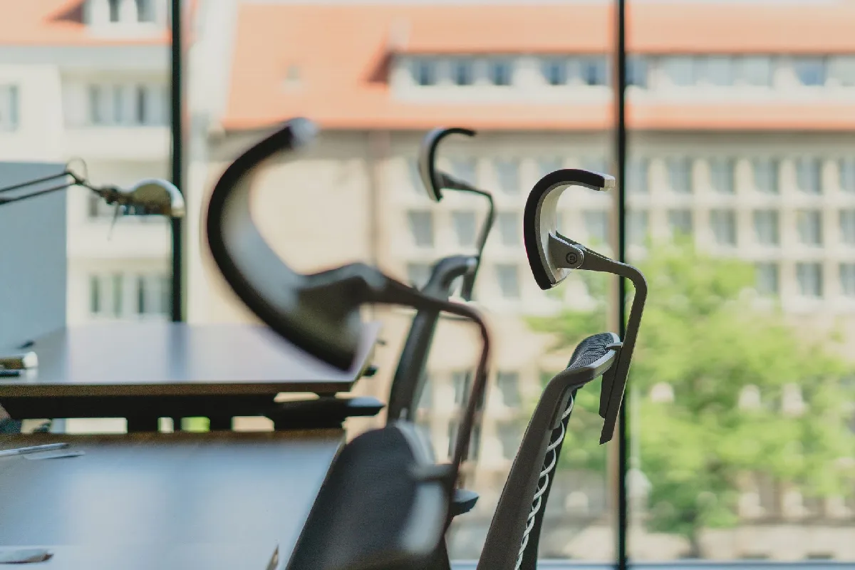 Como implementar Laudo Ergonômico NR-17 em Curitiba: Etapas Escritório moderno vazio com cadeiras elegantes e janelas amplas com vista para prédios da cidade. — Medicina Ocupacional Curitiba