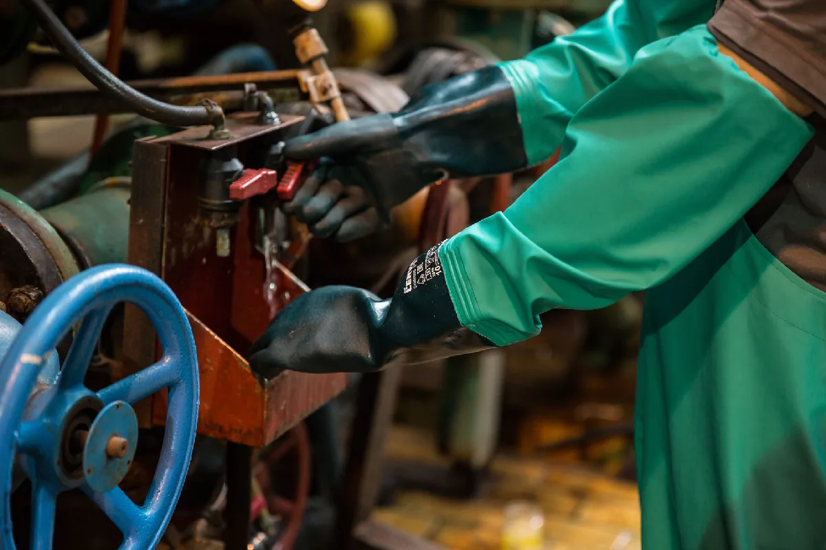 Como implementar PPR em Curitiba: Fluxo para Indústrias Trabalhador em fábrica com EPI manuseia válvula com precisão. — Medicina Ocupacional Curitiba