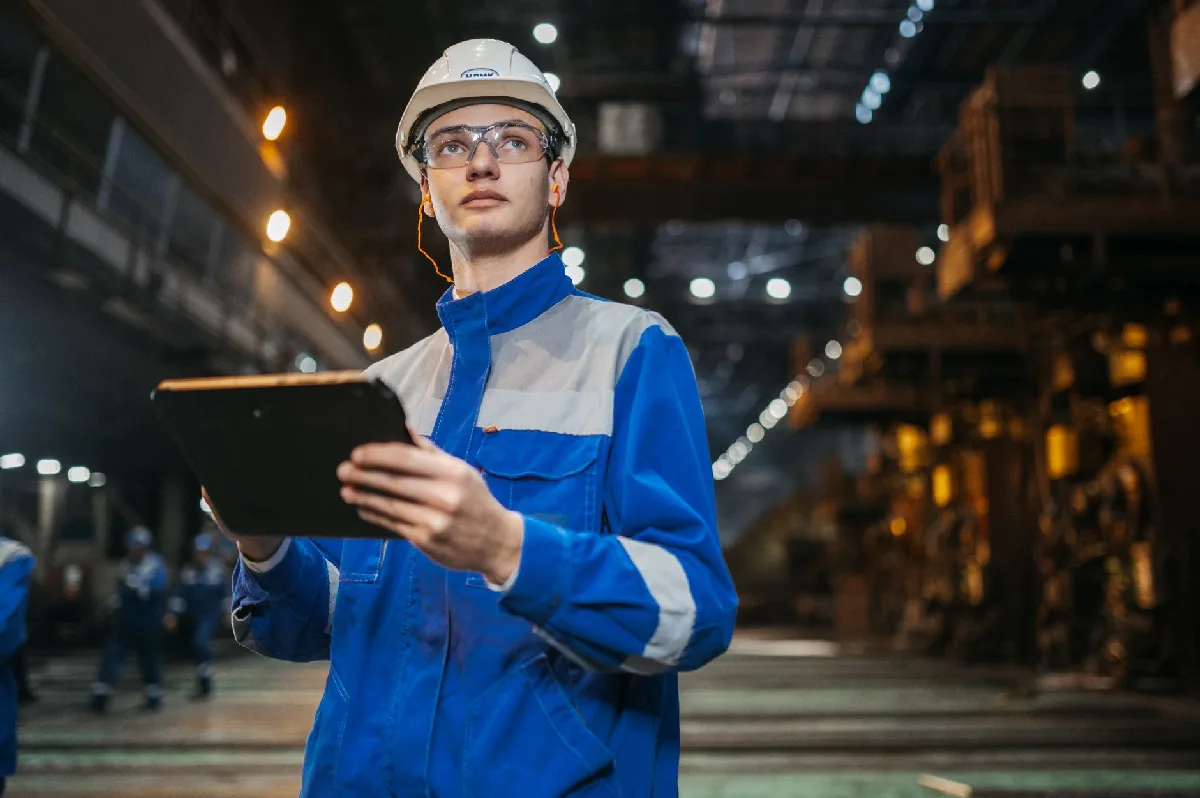 Engenheiro de segurança usa tablet em fábrica industrial, focado e diligente. — Medicina Ocupacional Curitiba