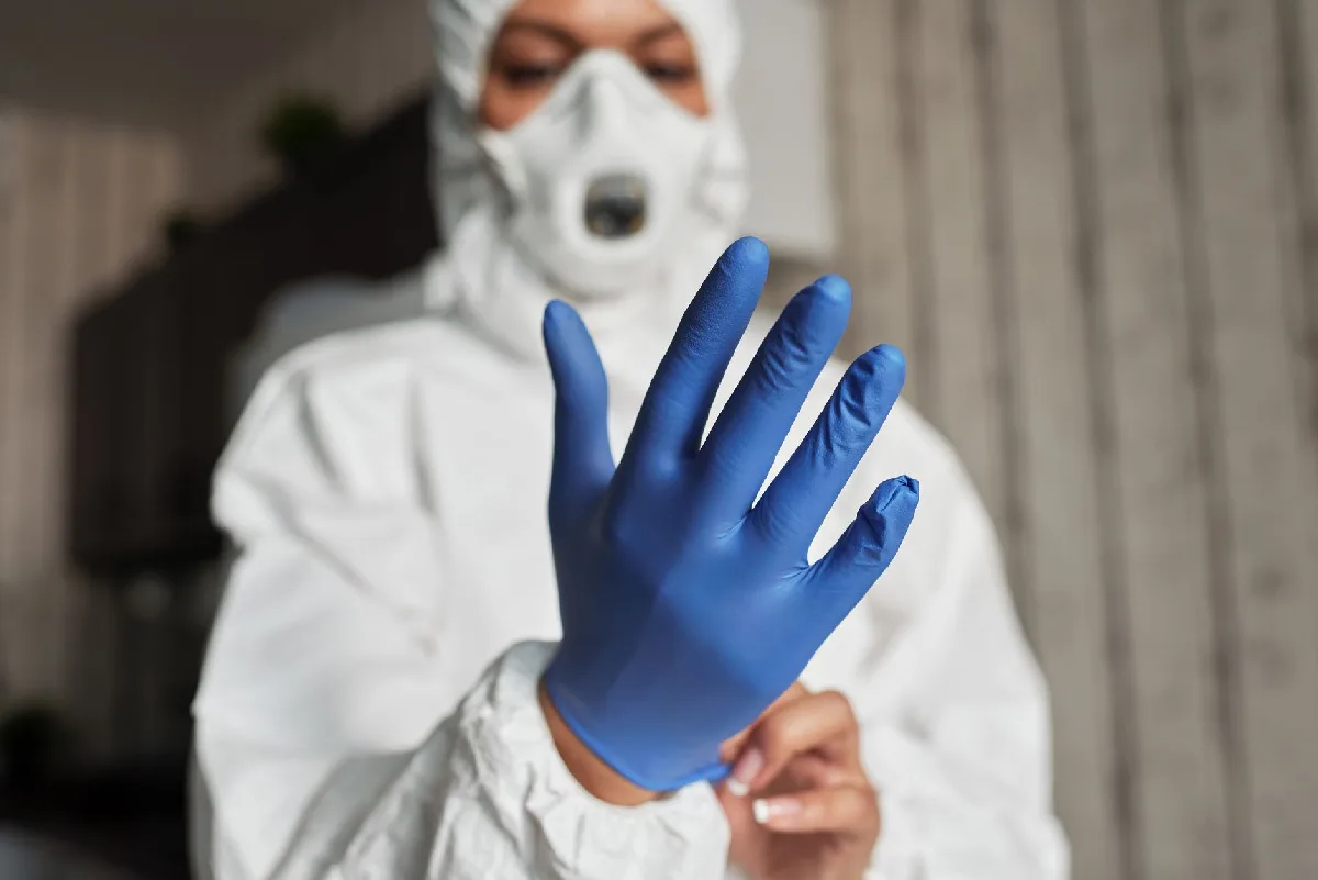 Ficha de EPI em Curitiba: Gestão de Passivos e Registros Profissional de saúde calçando luvas azuis de látex para proteção. — Medicina Ocupacional Curitiba