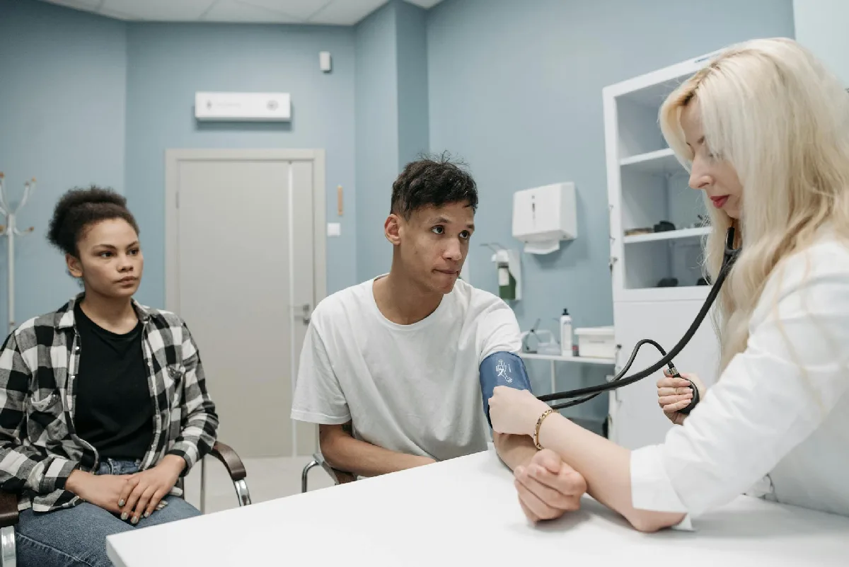 Programa de Controle Médico Curitiba: o que sua empresa precisa cumprir Médico mede pressão arterial de paciente com acompanhante em consultório. — Medicina Ocupacional Curitiba