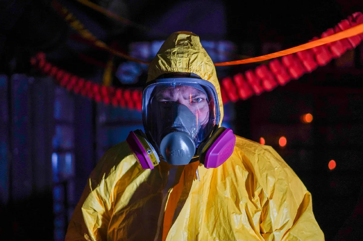 Pessoa com traje de proteção e máscara de gás em ambiente industrial. — Medicina Ocupacional Curitiba